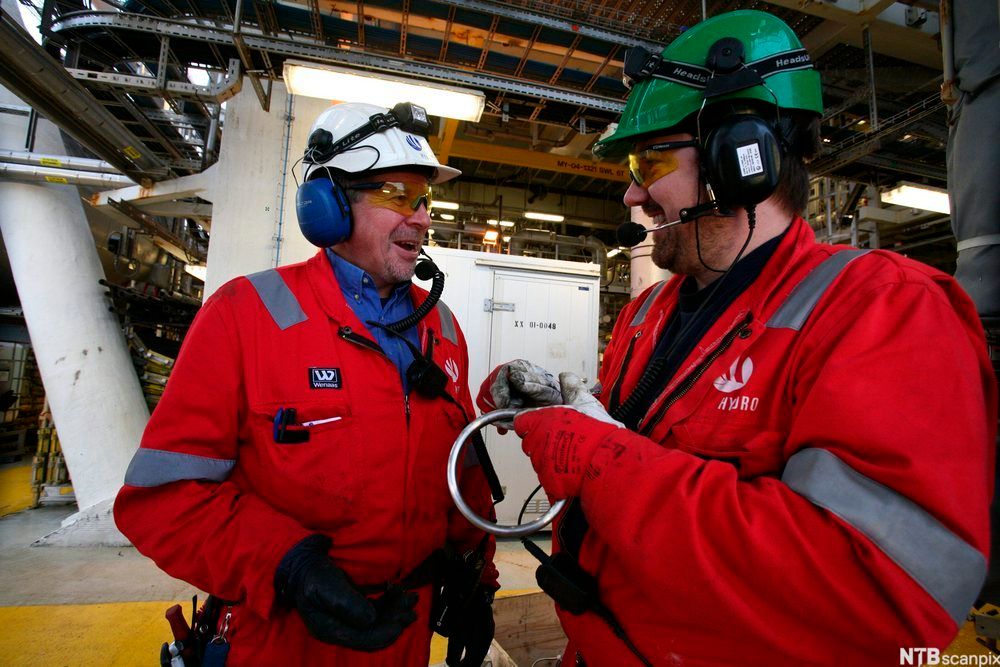 To menn med verneutstyr snakker sammen. Foto.