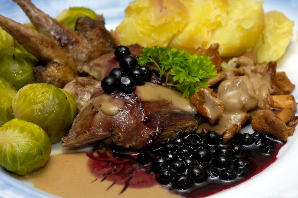 Rypebryst med rosenkål og mandelpoteter, servert med viltsaus og rypebærsyltetøy. Foto.