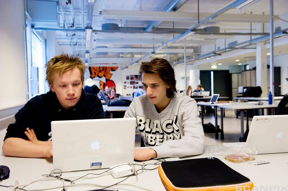 To gutter i et klasserom som jobber sammen på en datamaskin. Foto.