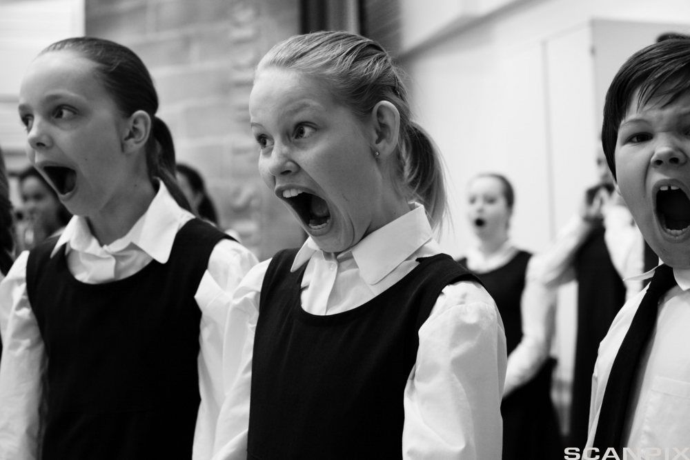 Barn som synger i kor, med munnen på vidt gap. Foto.