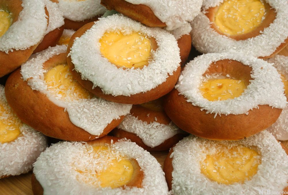 Hveteboller fylt med vaniljekrem, pyntet med melis og kokos. Foto.