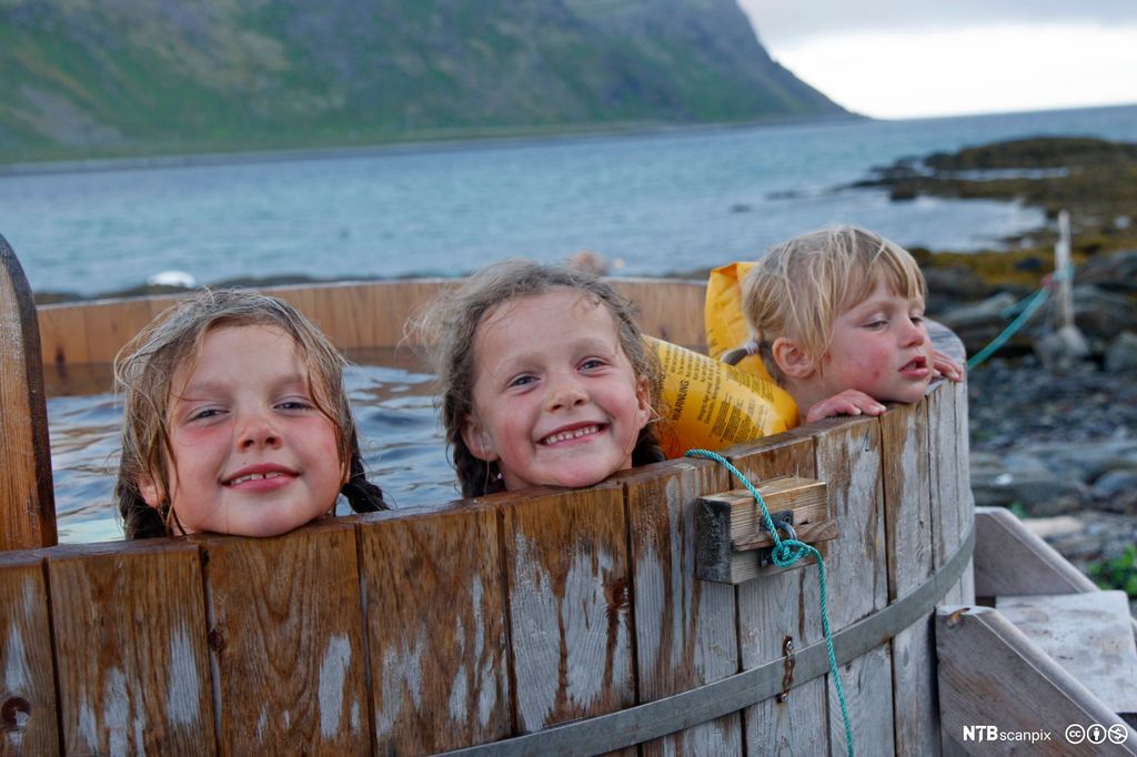 Tre jenter bader i badestamp ut mot havet. Foto.