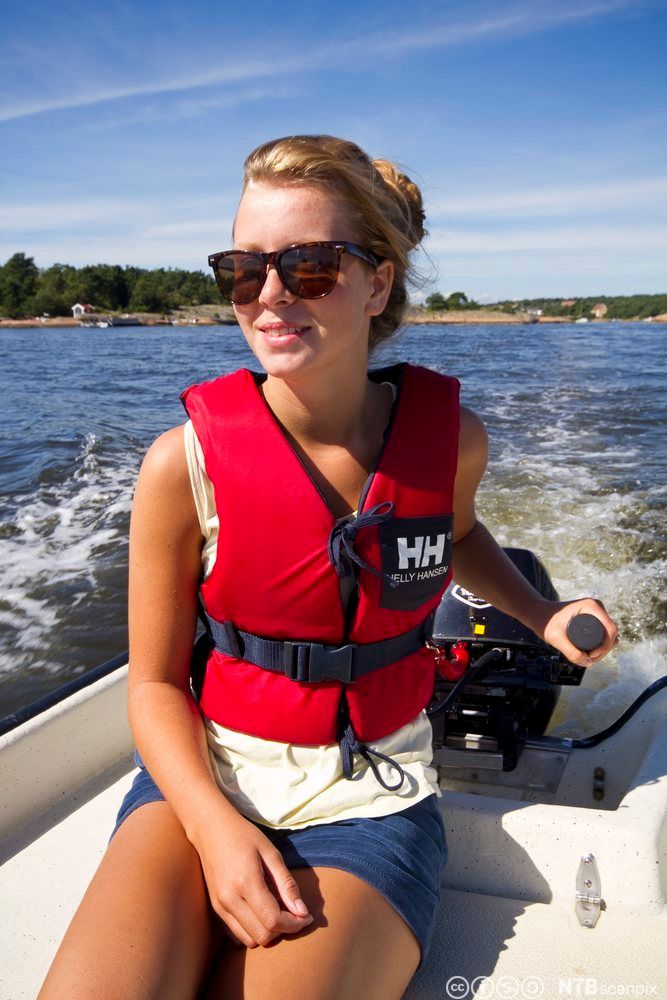 Jente styrer småbåt med påhengsmotor. Foto.