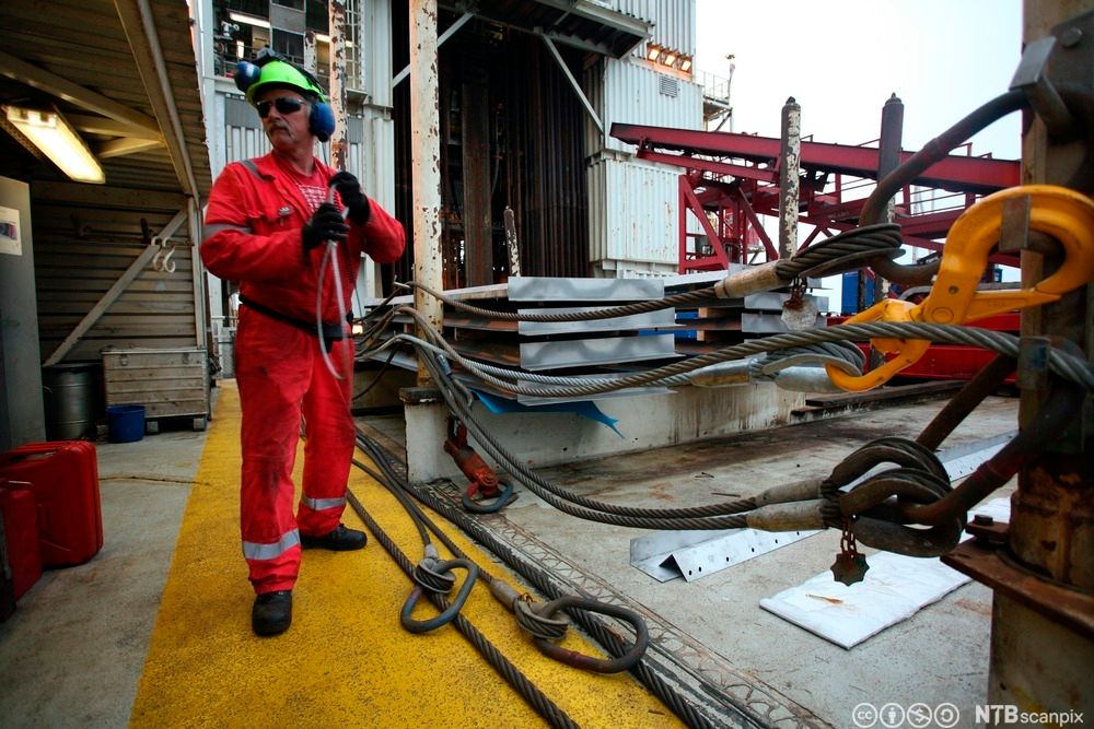 Bildet viser en boredekksarbeider som skal til å samle stålkabler i en strips, slik at området blir ryddig og sikkert. Foto.