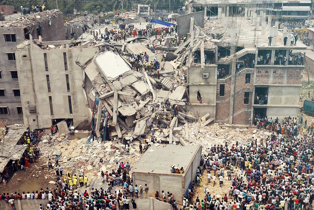 Store øydeleggingar etter ein bygning som er kollapsa, med mange menneske framfor, inni og oppå bygninga. Foto.