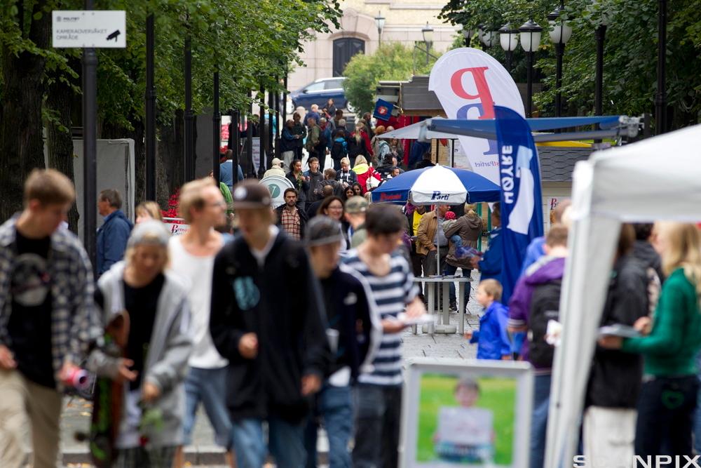 Ei gågate eller eit fortau med folkemylder. Representantar frå fleire politiske parti står på stand. Foto.