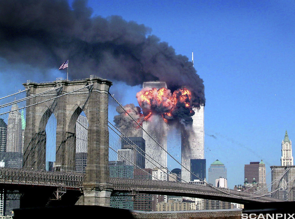 Brooklyn Bridge i forgrunnen og de to tvillingtårnene World Trade Center brennende i bakgrunnen. Foto.