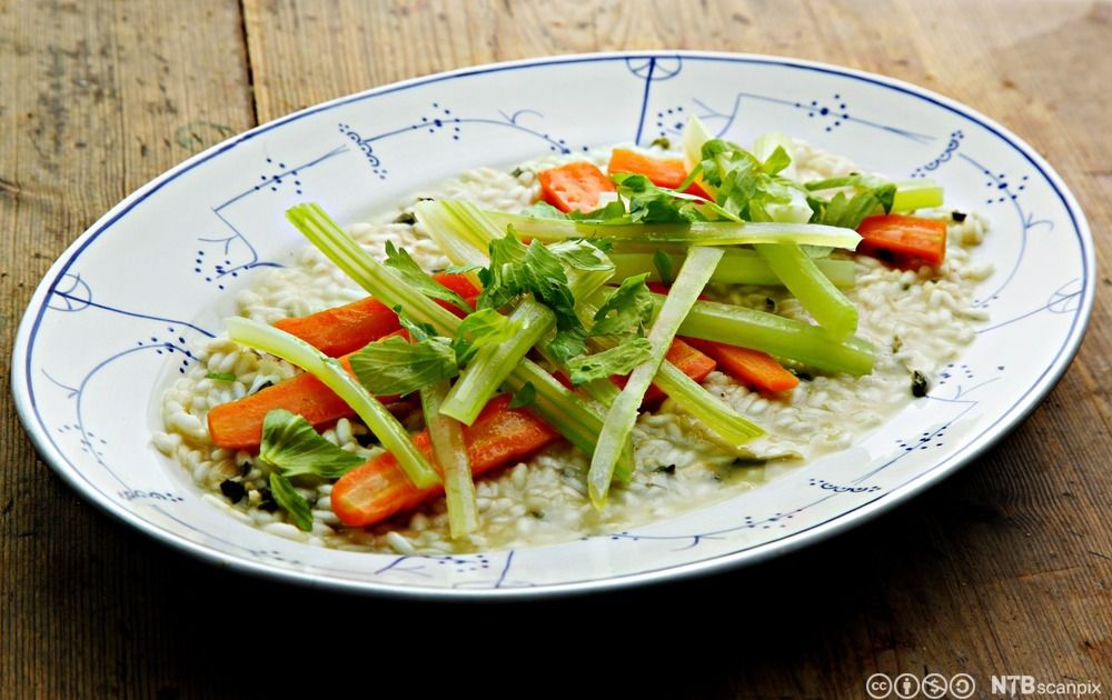 En avlang serveringstallerken med røde og grønne grønnsaker på hvit ris. Foto.