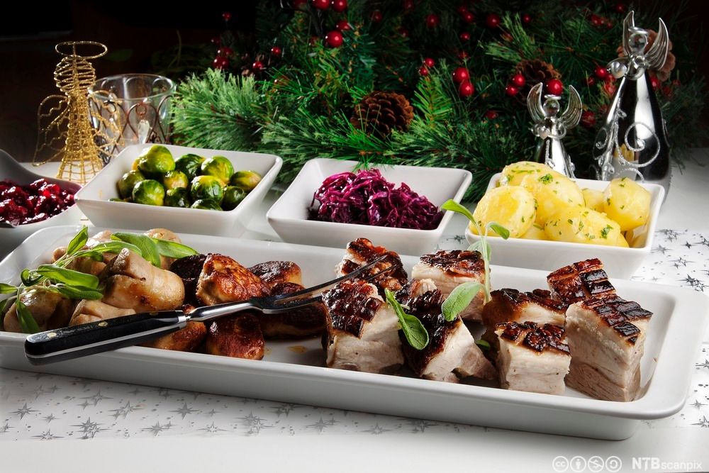 Ribbe på et fat med poteter, rødkål og rosenkål. Foto.