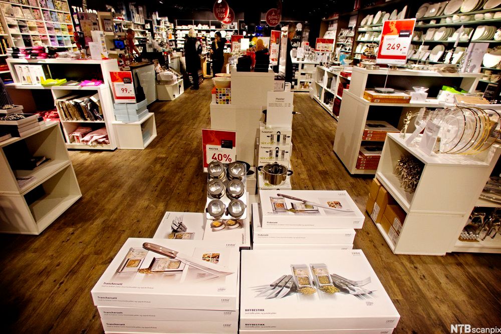 Knivsett, kjeler, middagsservise og lignende varer står utstilt på bord og i hyller i en kjøkken- og interiørbutikk. Foto.