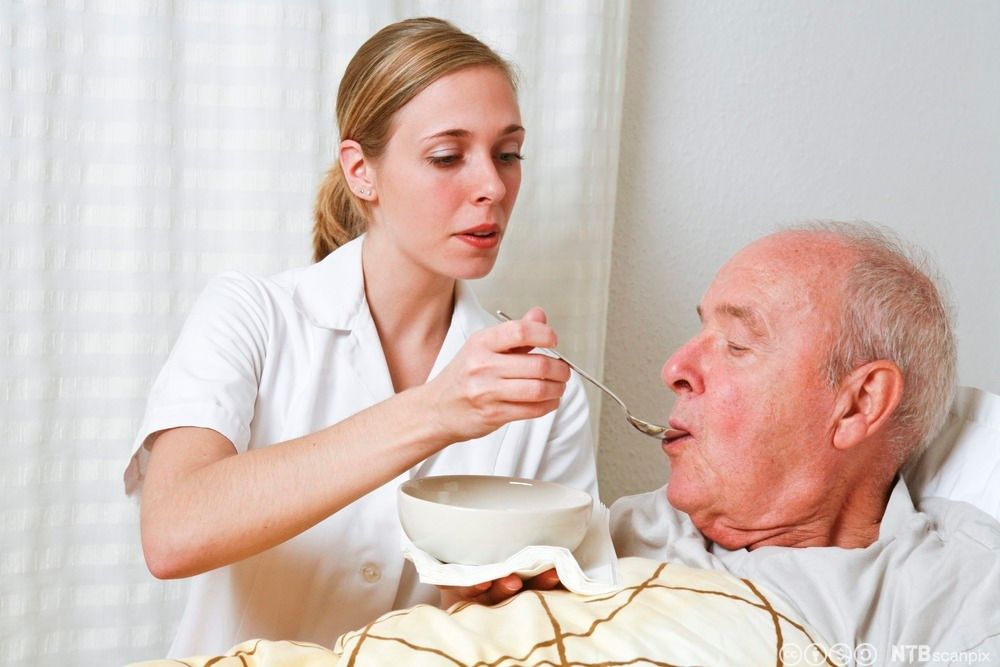 Eldre mann får hjelp med måltidet. Foto.