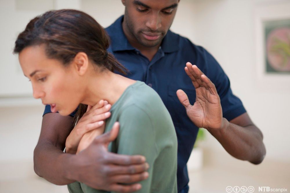 En kvinne strever med å puste. En person forsøker å hjelpe ved å slå henne i ryggen. Foto.
