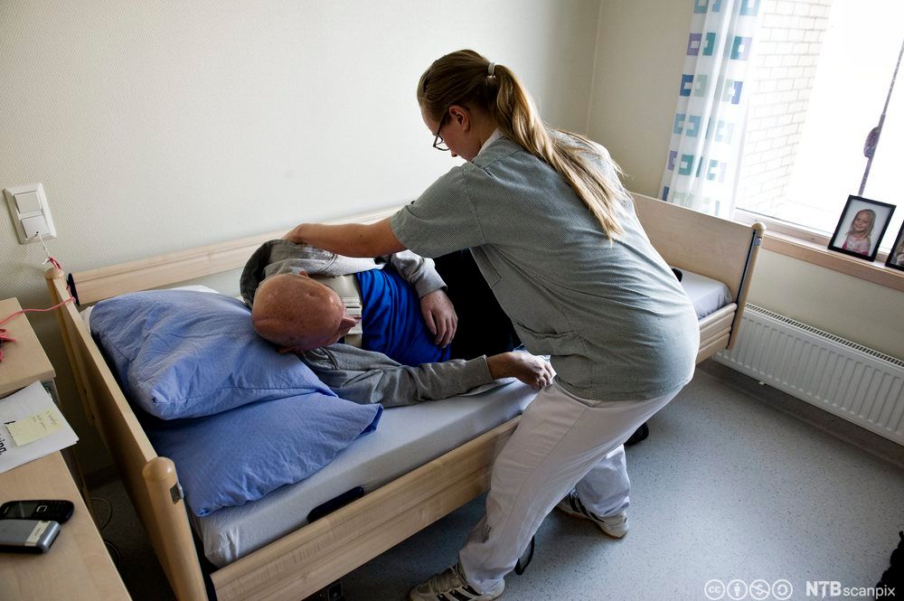 Pleier hjelper slagrammet pasient med å legge seg til rette og snu seg i sengen. Foto.