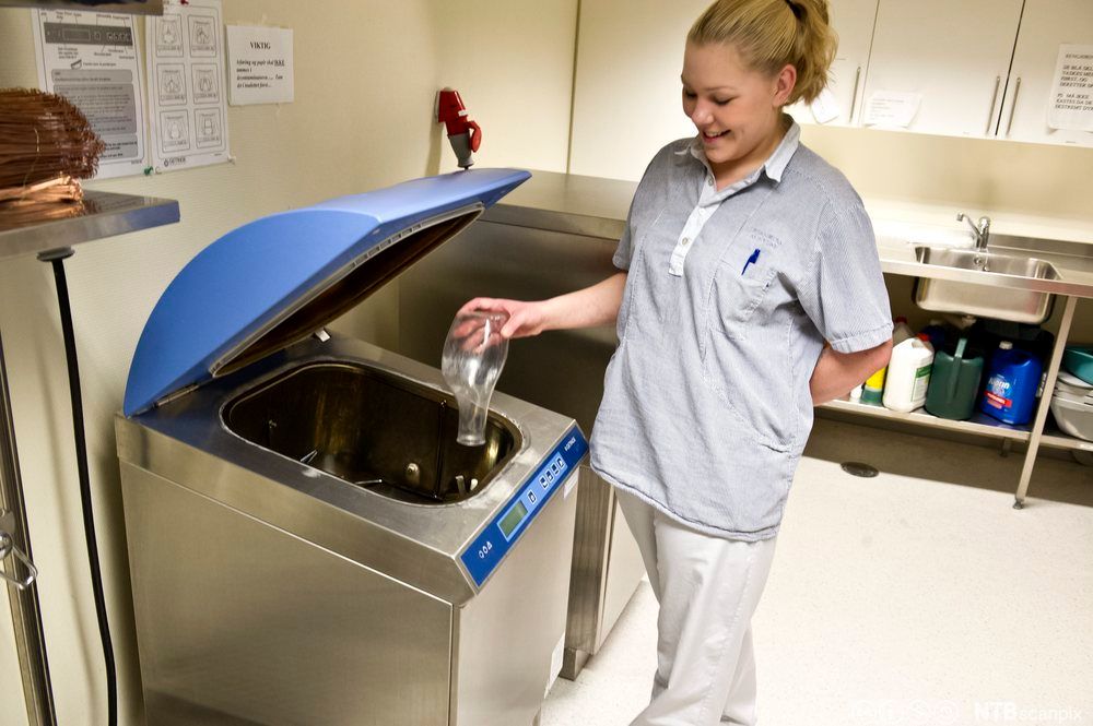 Helsefagarbeider som desinfiserer utstyr på skyllerommet. Foto.