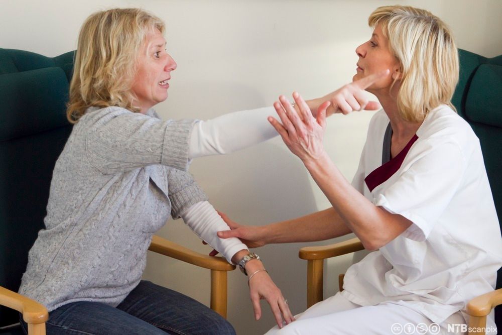 Helsefagarbeider diskuterer med pårørende. Foto.