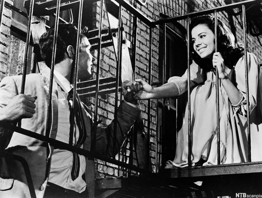 Scene fra West Side Story som viser hovedpersonene Tony og Maria. De befinner seg på branntrappa i bakgården på en slitt mursteinsbygning