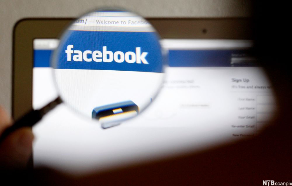 Et forstørrelsesglass holdes over Facebook-logoen på en PC-skjerm. Foto.