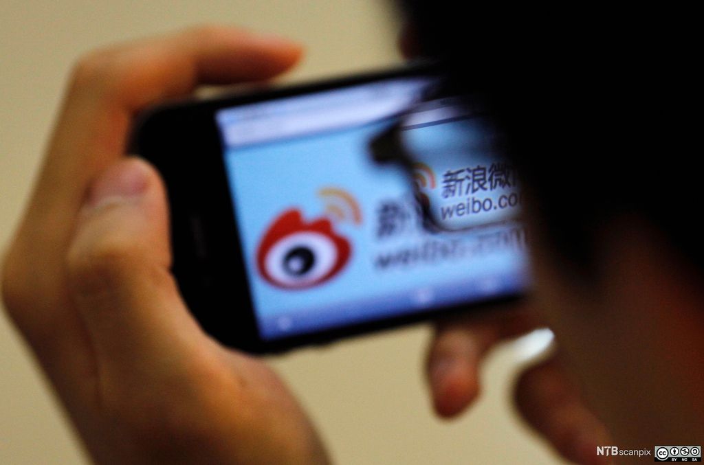 Mann bruker appen Sina Weibo på en mobiltelefon. Foto.