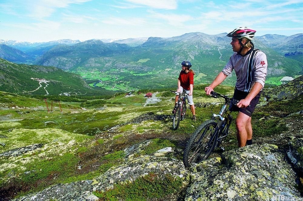 To personer på sykkel i vakkert fjellandskap. Foto.