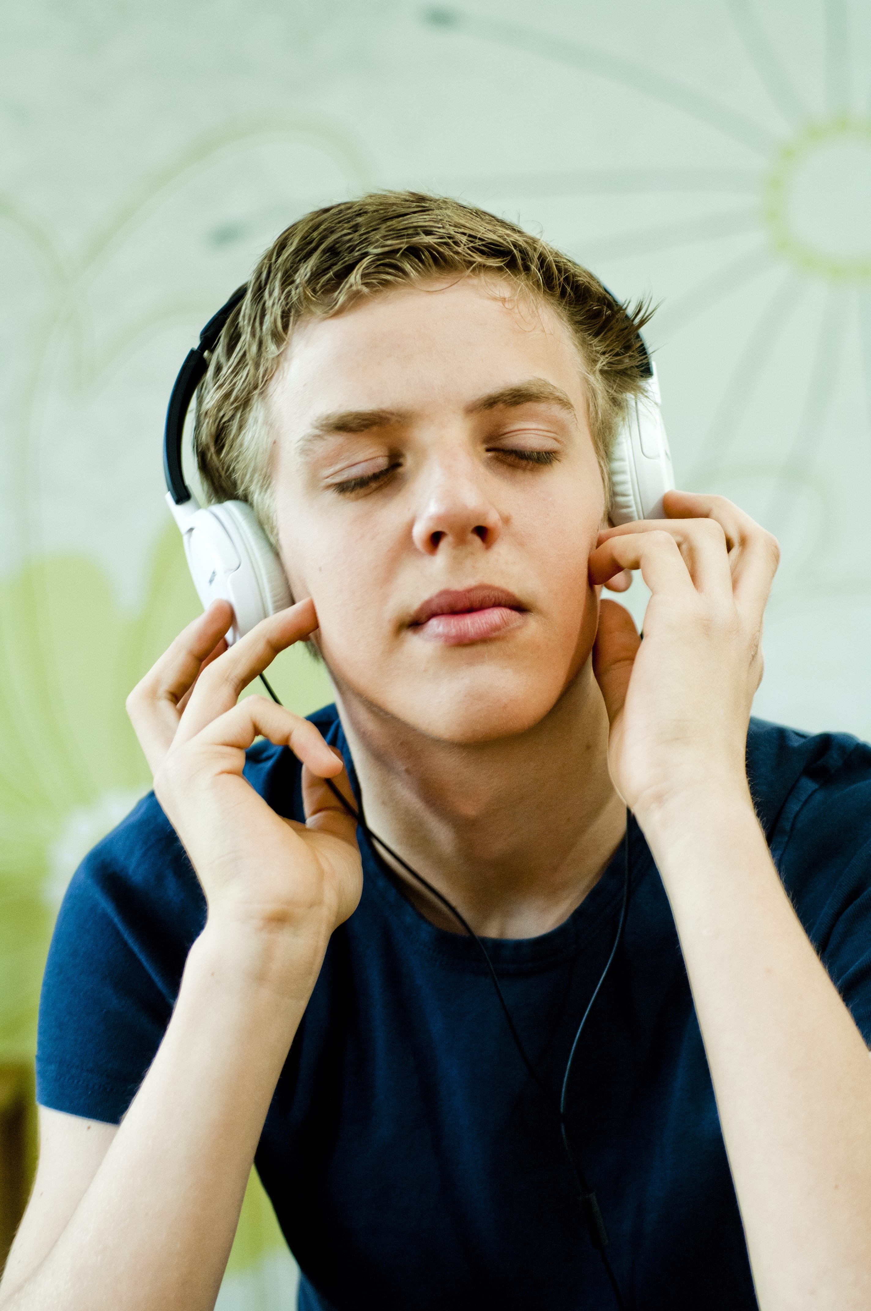 Foto av gutt med øreklokker som lytter med lukkede øyne.