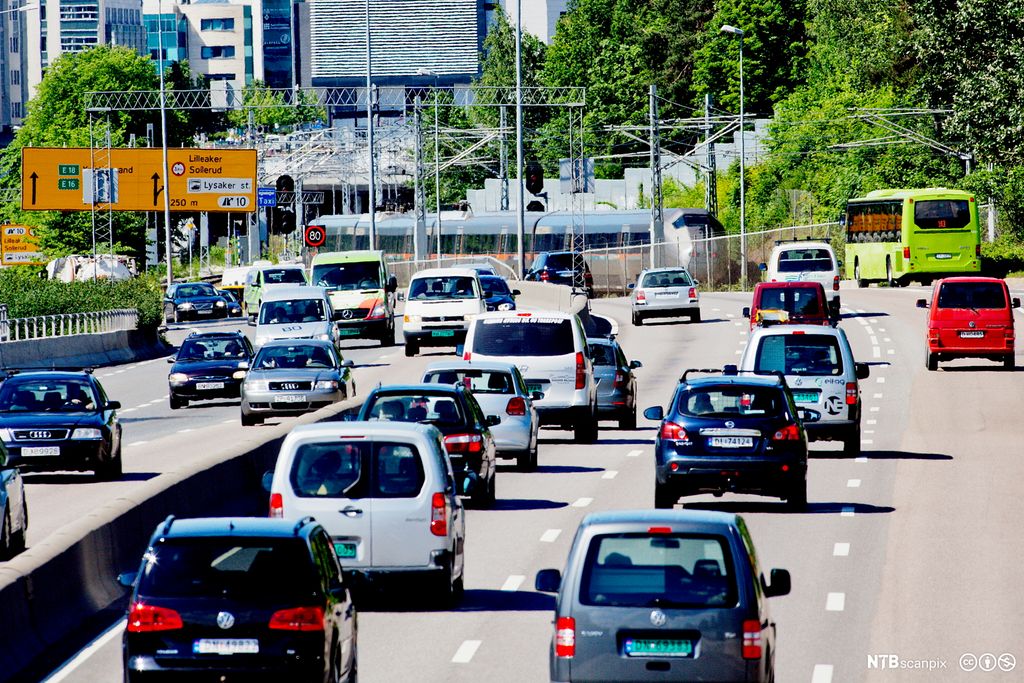 Tog og biltrafikk på E18 før avkjøring til Lysaker stasjon. Foto.