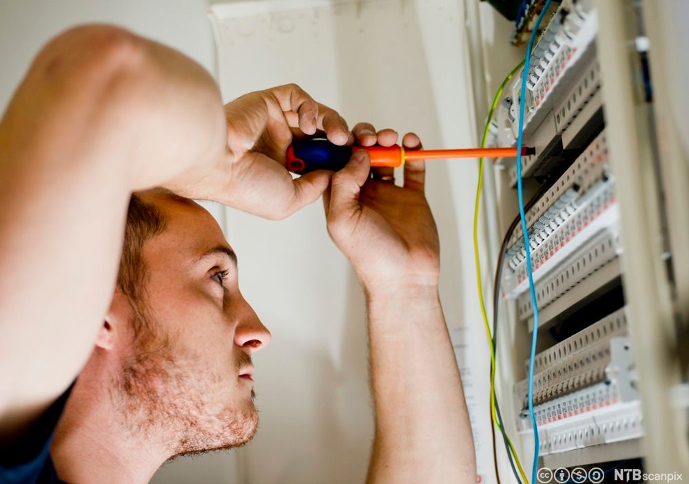 Elektriker som skrur i et sikringsskap i en privatbolig. Foto.