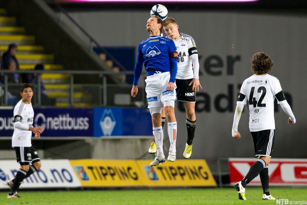 Fotballkamp mellom Molde og Rosenborg. En spiller fra hvert lag hopper samtidig for å prøve å heade ballen. Foto.