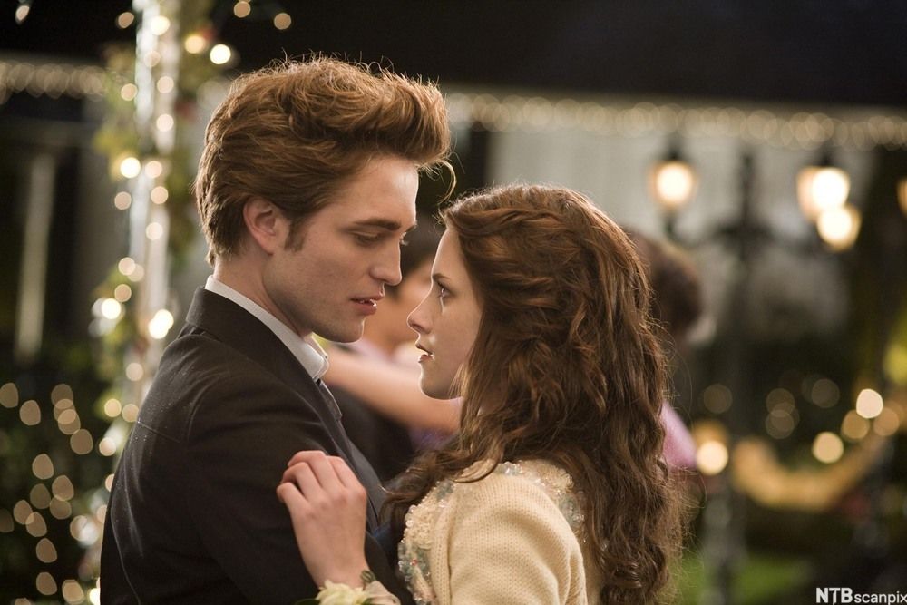 Nærbilete av hovudpersonane Bella Swan og Edward Cullen i filmatiseringa av romanen "Twilight". Dei to står tett inntil kvarandre og ser kvarandre i auga. Foto.