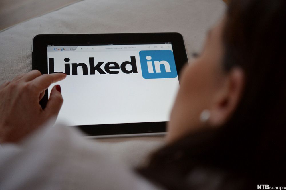 Kvinne ser på LinkedIn-siden på et nettbrett. Foto.