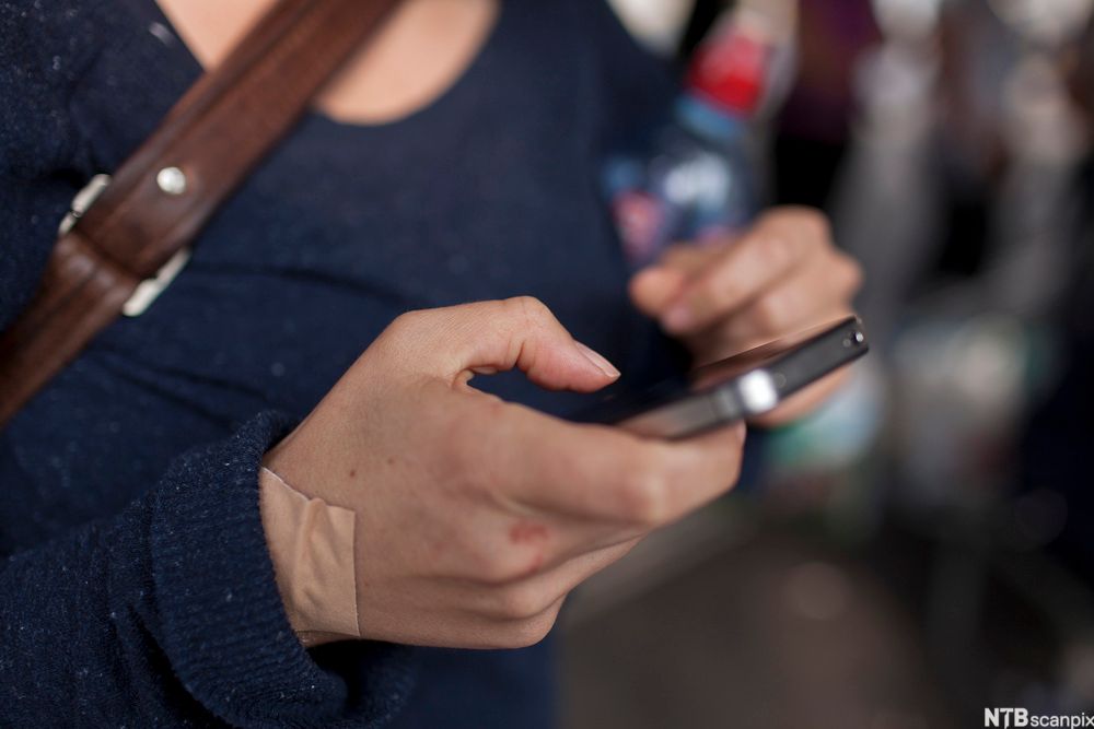 Bilde av en kvinne som taster på sin iPhone.