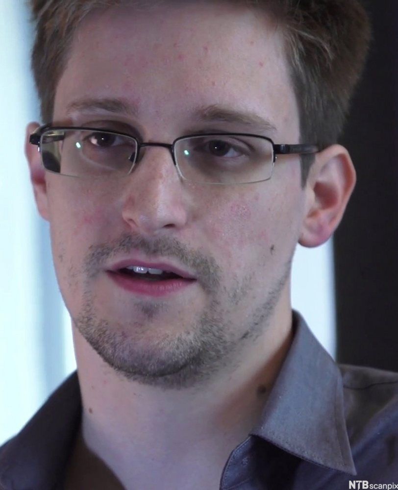Portrett av Edward Snowden, en ung mann med kort hår, briller og skjeggstubber. Foto.