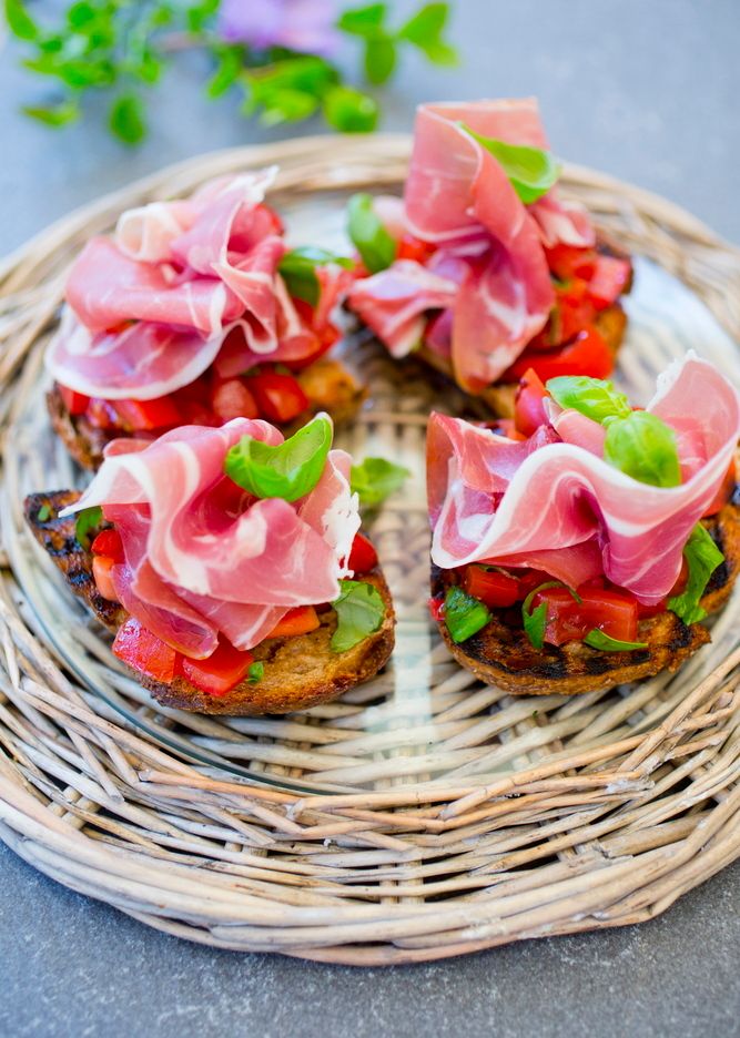 Fire fargerike bruschetta serverte på eit rundt rottingfat. Foto.