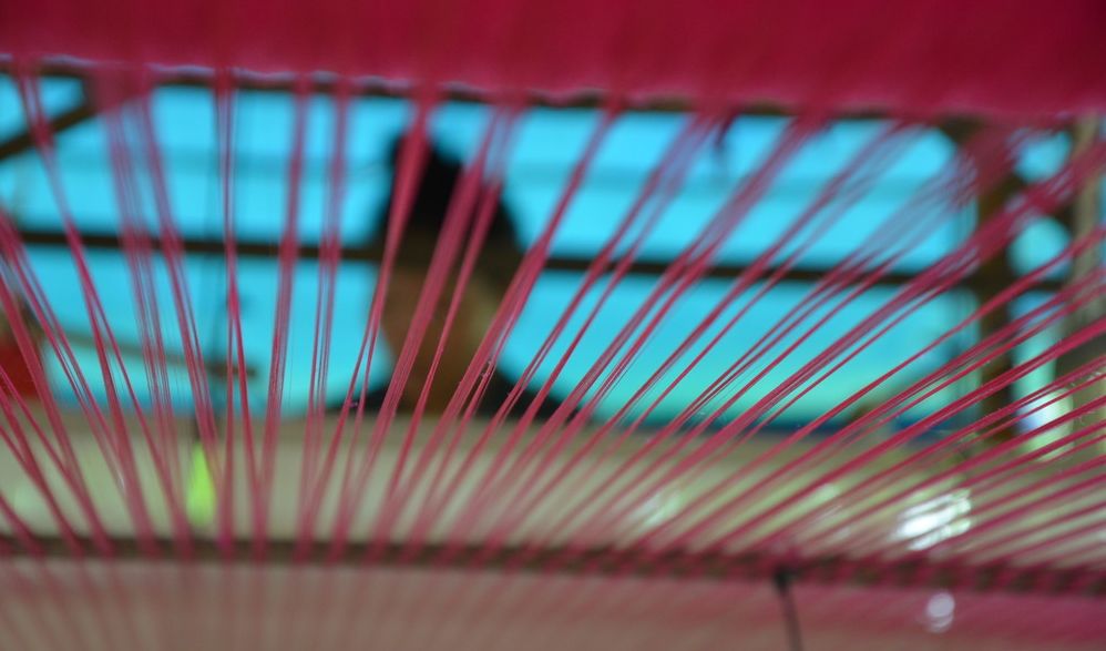 Nærbilete av renning og innslag i ein vev. Foto.