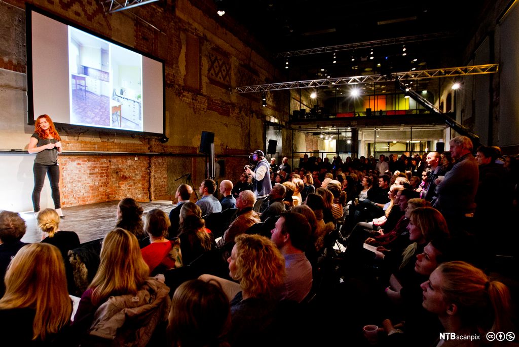 Kvinne på en scene holder en PechaKucha-presentasjon. Foto