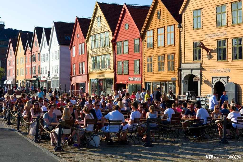 Folk hygger seg på uterestaurant på Bryggen i Bergen. Foto.
