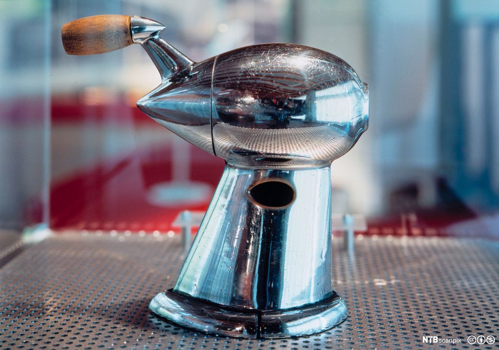 Blyantspisser i sølv med sveiv i tre i monter. Foto.