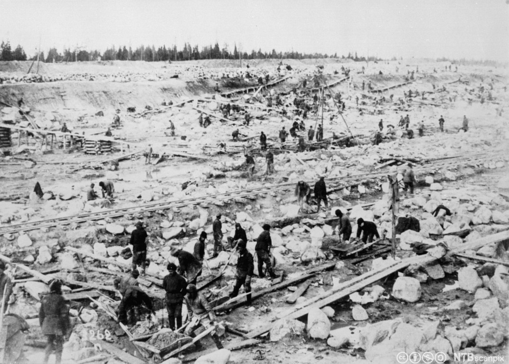 Et stort område med mye stor stein og fanger som arbeider hardt fysisk. Foto. 