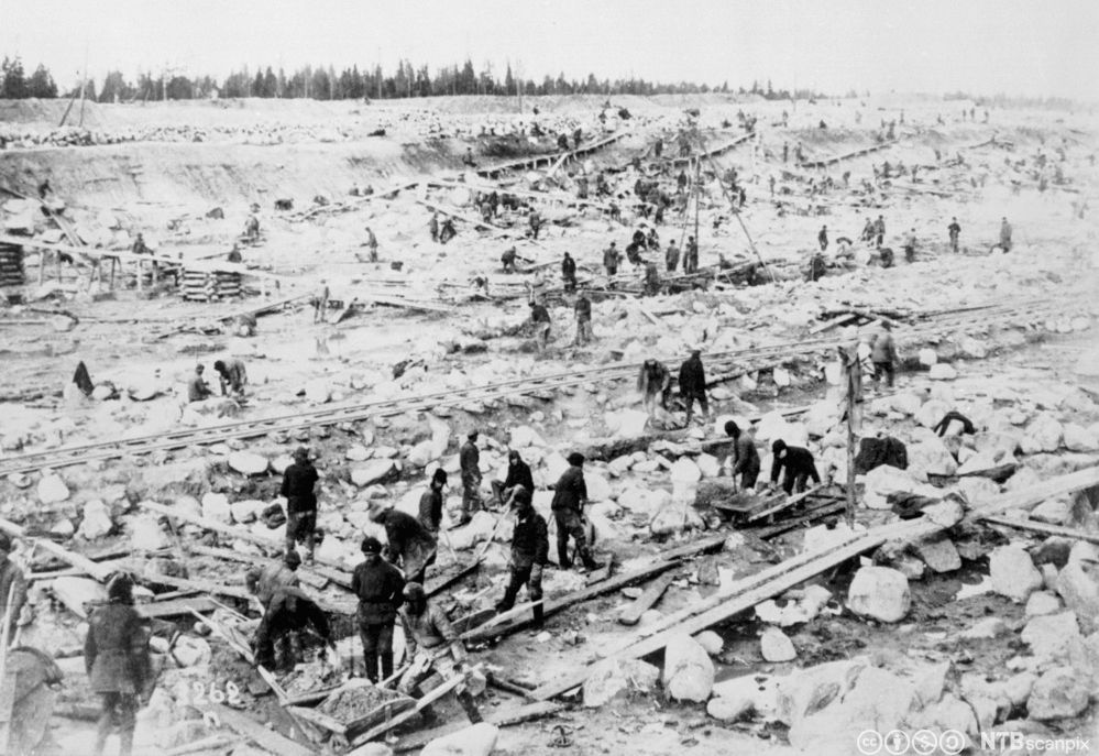 Et stort område med mye stor stein og fanger som arbeider hardt fysisk. Foto.