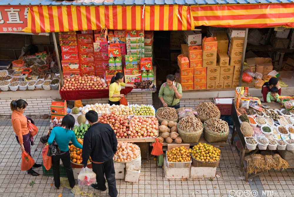 Kunder studerer utvalget i en frukt- og grønnsaksbod i Kina. Foto.
