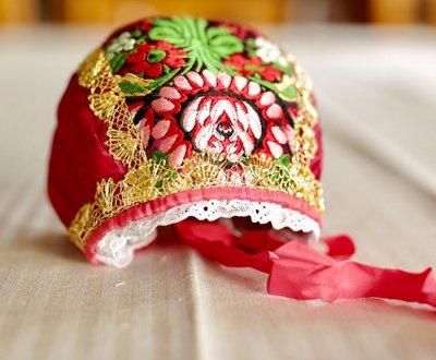 Brodert, flerfarga bunadslue med bånd. Foto.