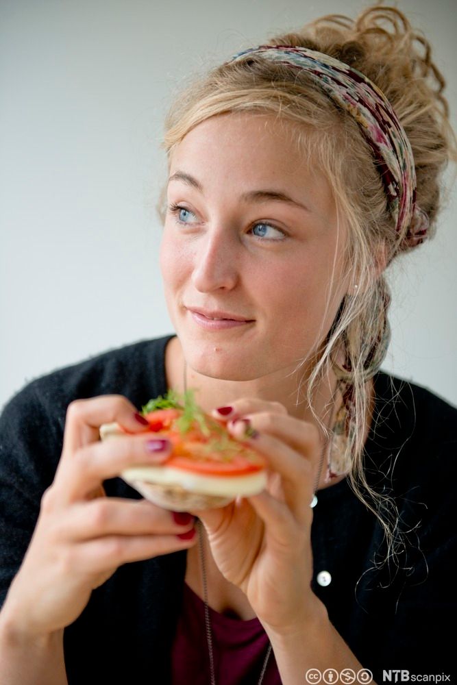 Ung jente som spiser brødskive med hvitost. Foto.