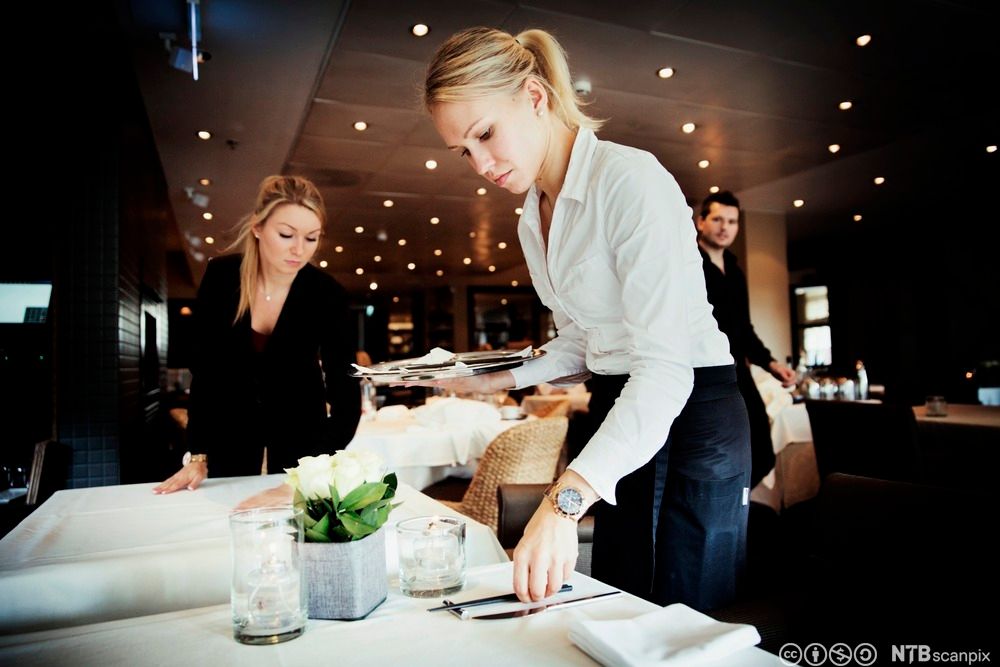 To servitører dekker et bord i en restaurant. Foto.
