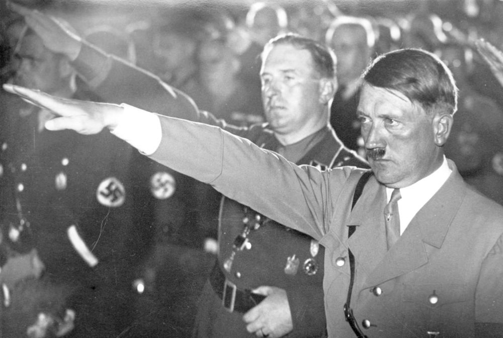 Adolf Hitler og andre menn i naziuniform gjør nazi-hilsen. Foto.