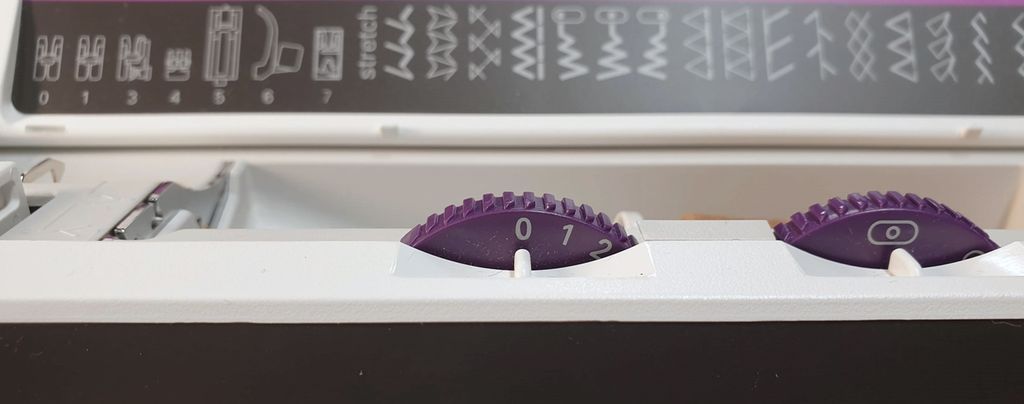 Fotografi av at tannhjulet til venstre er stilt inn på 0, og at ikonet på tannhjulet til høyre viser at nålen er midtstilt.