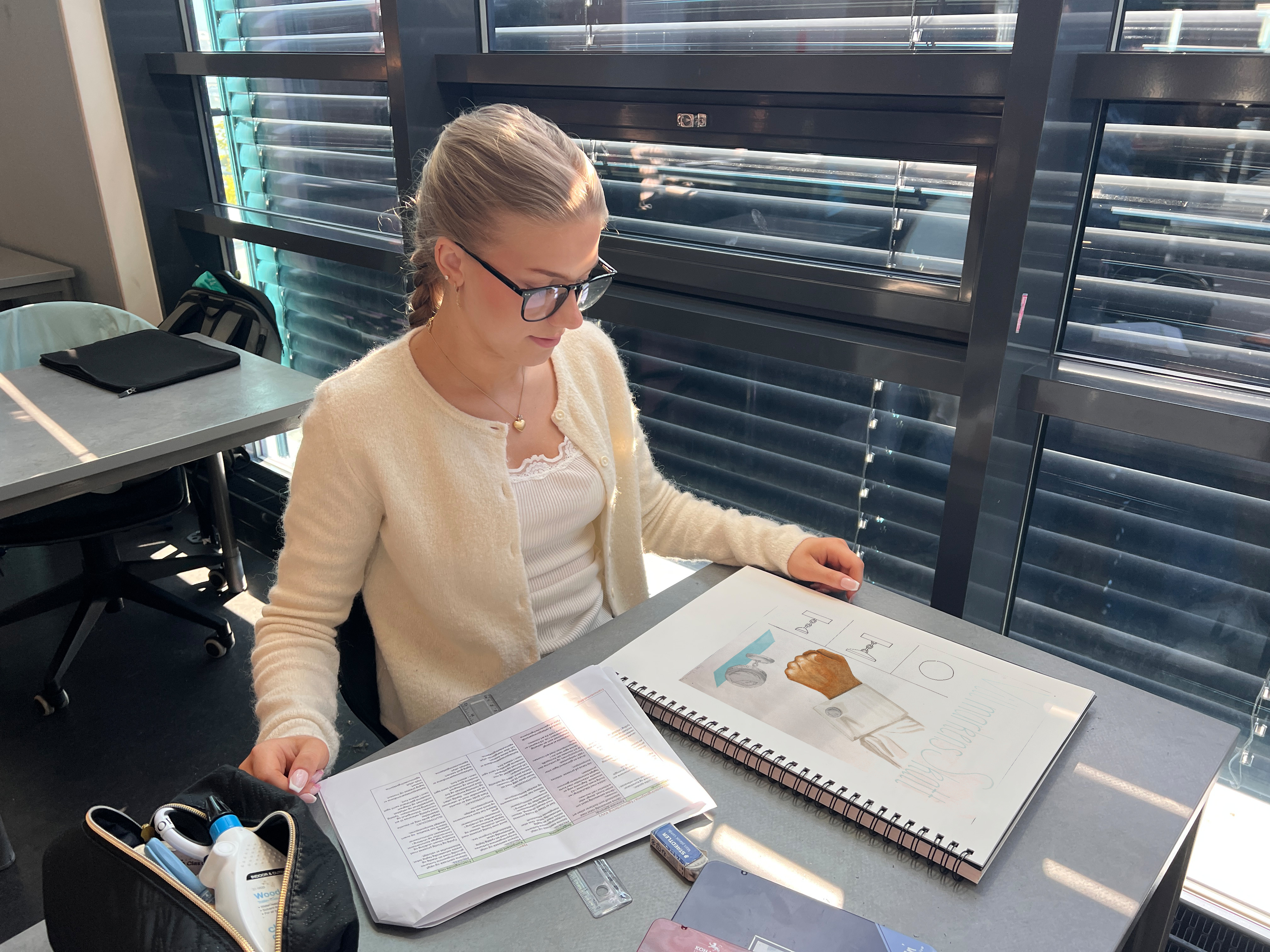 Elev som ser på en tegning i skisseboka. Foto.