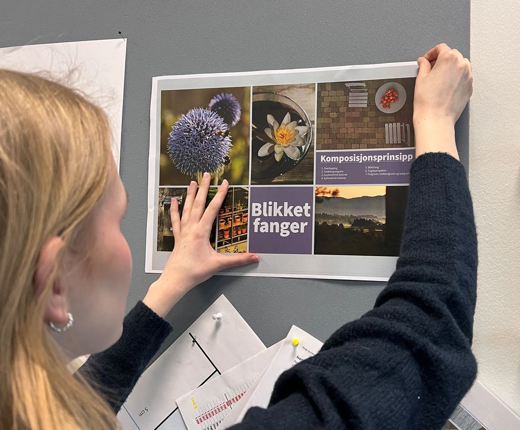 Elev henger opp en plakat på en vegg. Foto.