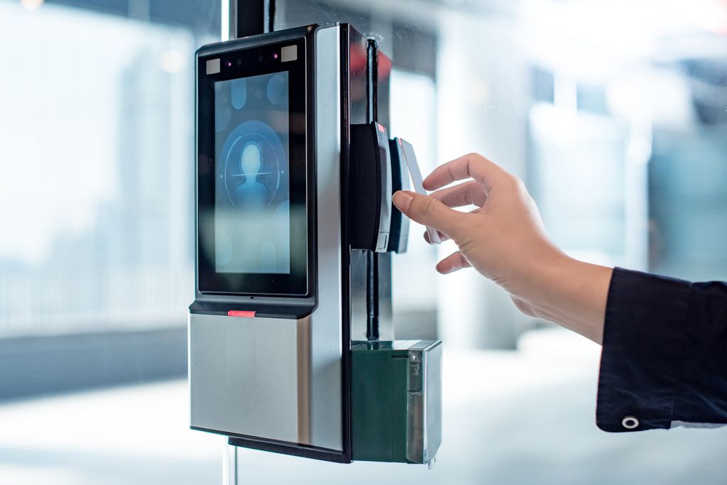 Hånd som holder et nøkkelkort mot en elektronisk skannner på en dør. Foto.