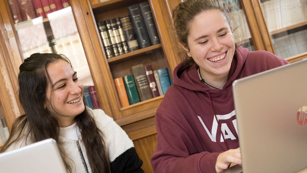 To smilende jenter ser på en pc. Foto.