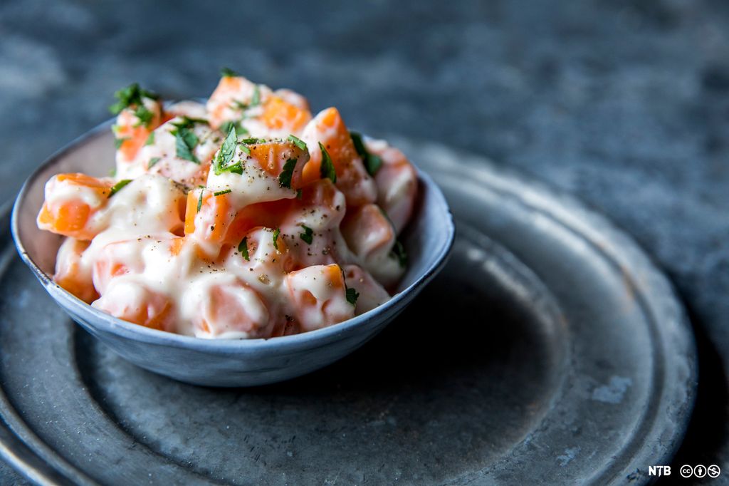 Stuet gulrot i en blå skål. Foto.