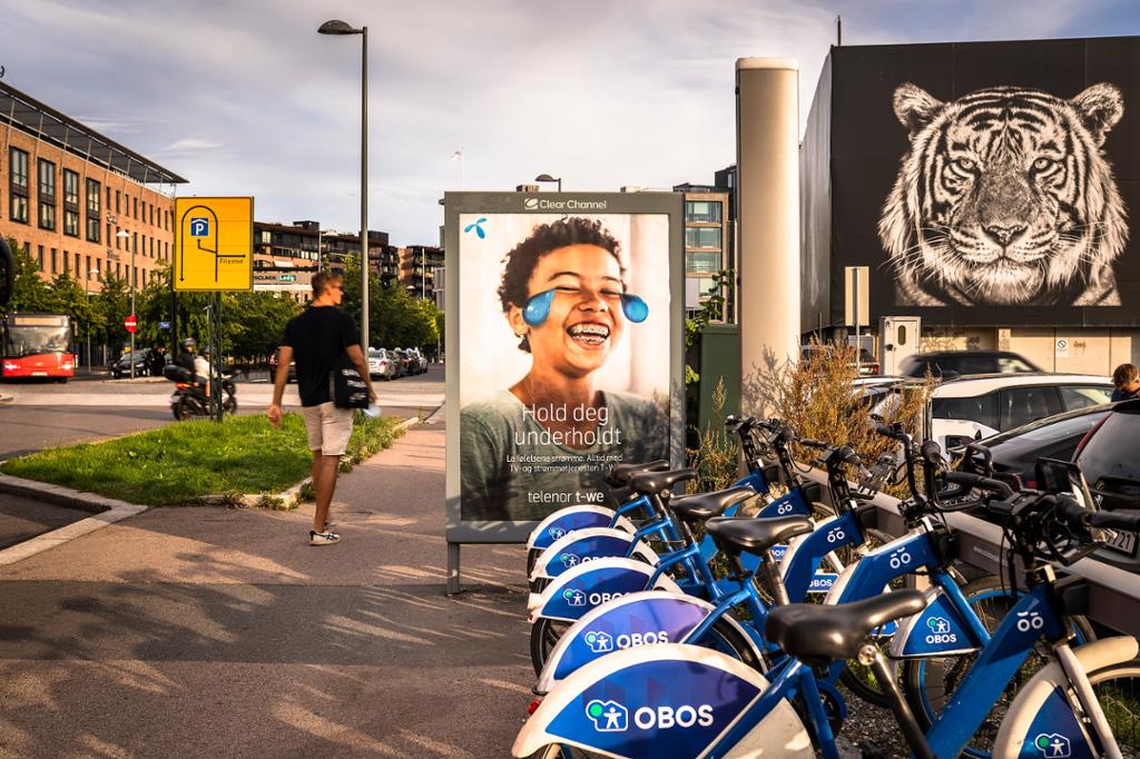 Utleigesyklar og reklameskilt i eit byrom. Foto.